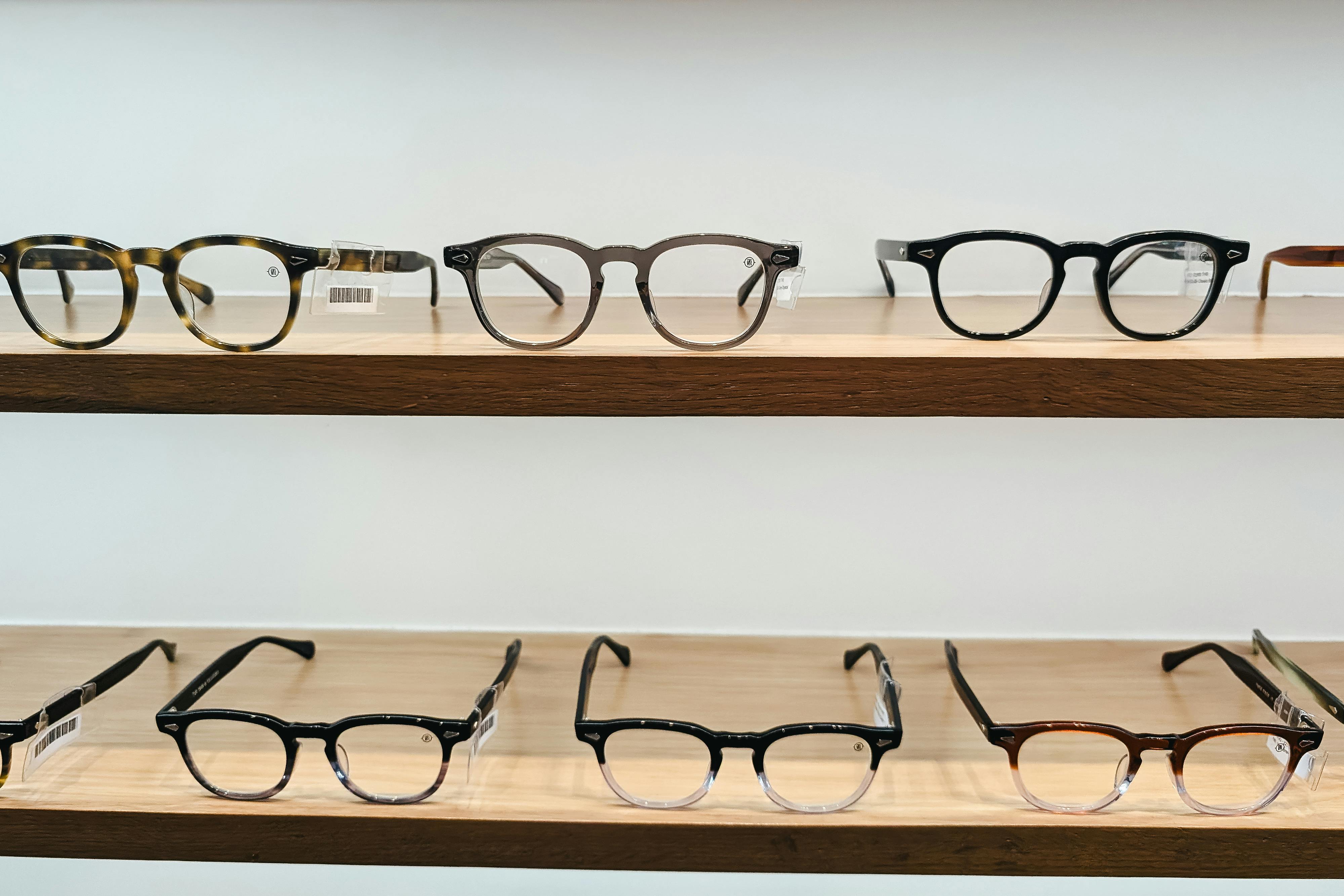 A row of glasses on a shelf with wooden shelves