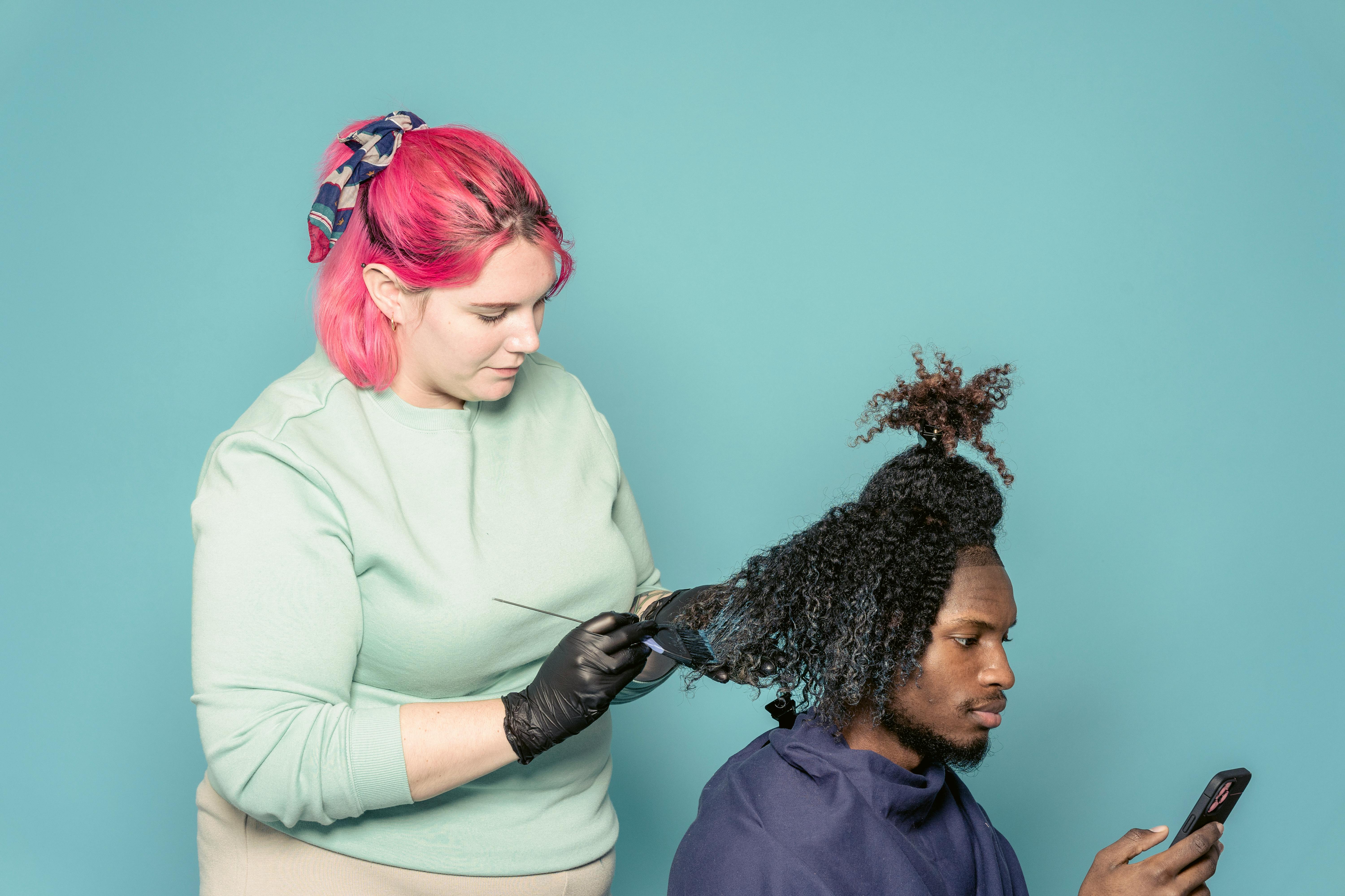 Hairdresser applying paint on hair of black client