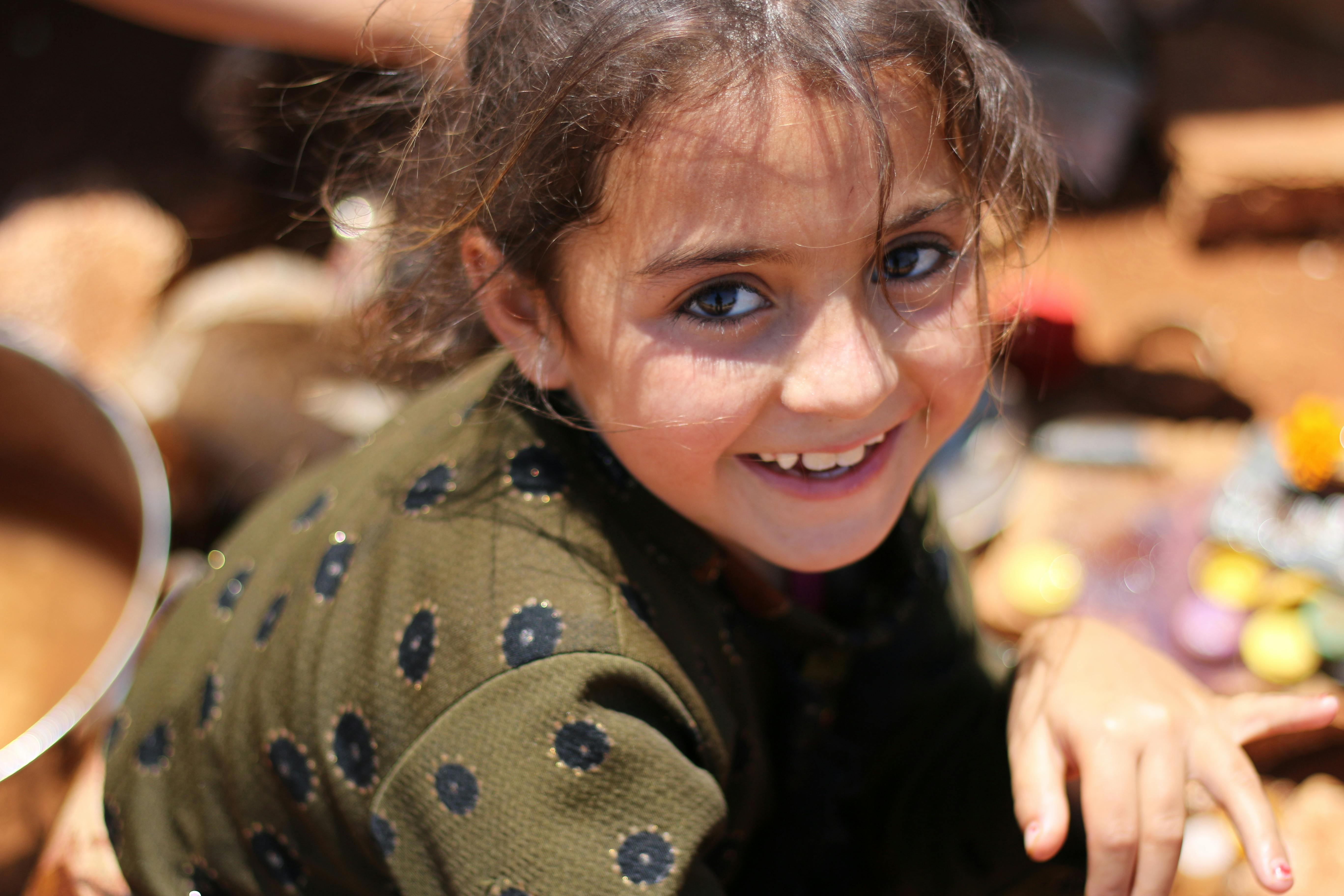 A young girl smiles while sitting on a bench