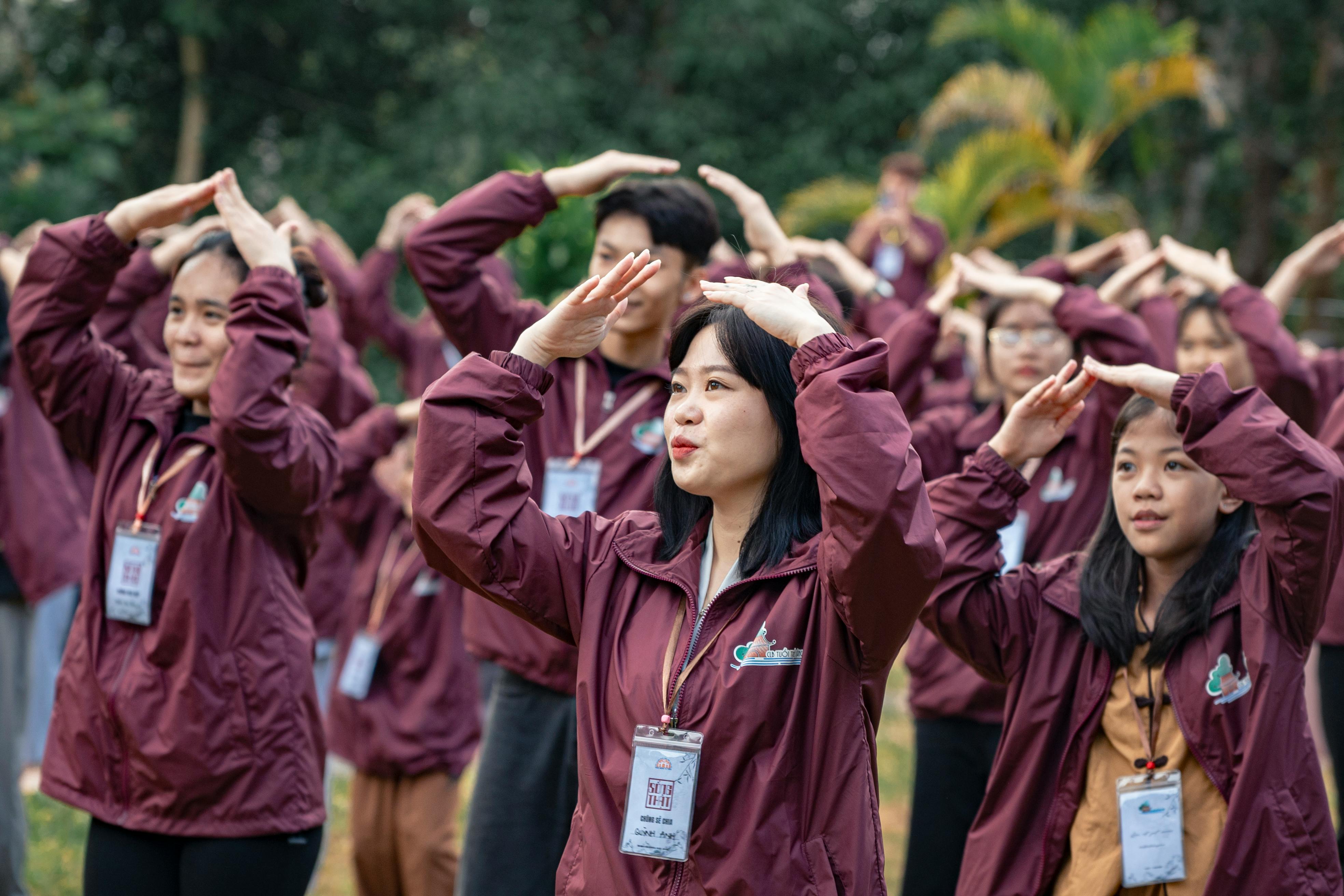 A group of people in maroon jackets doing yoga