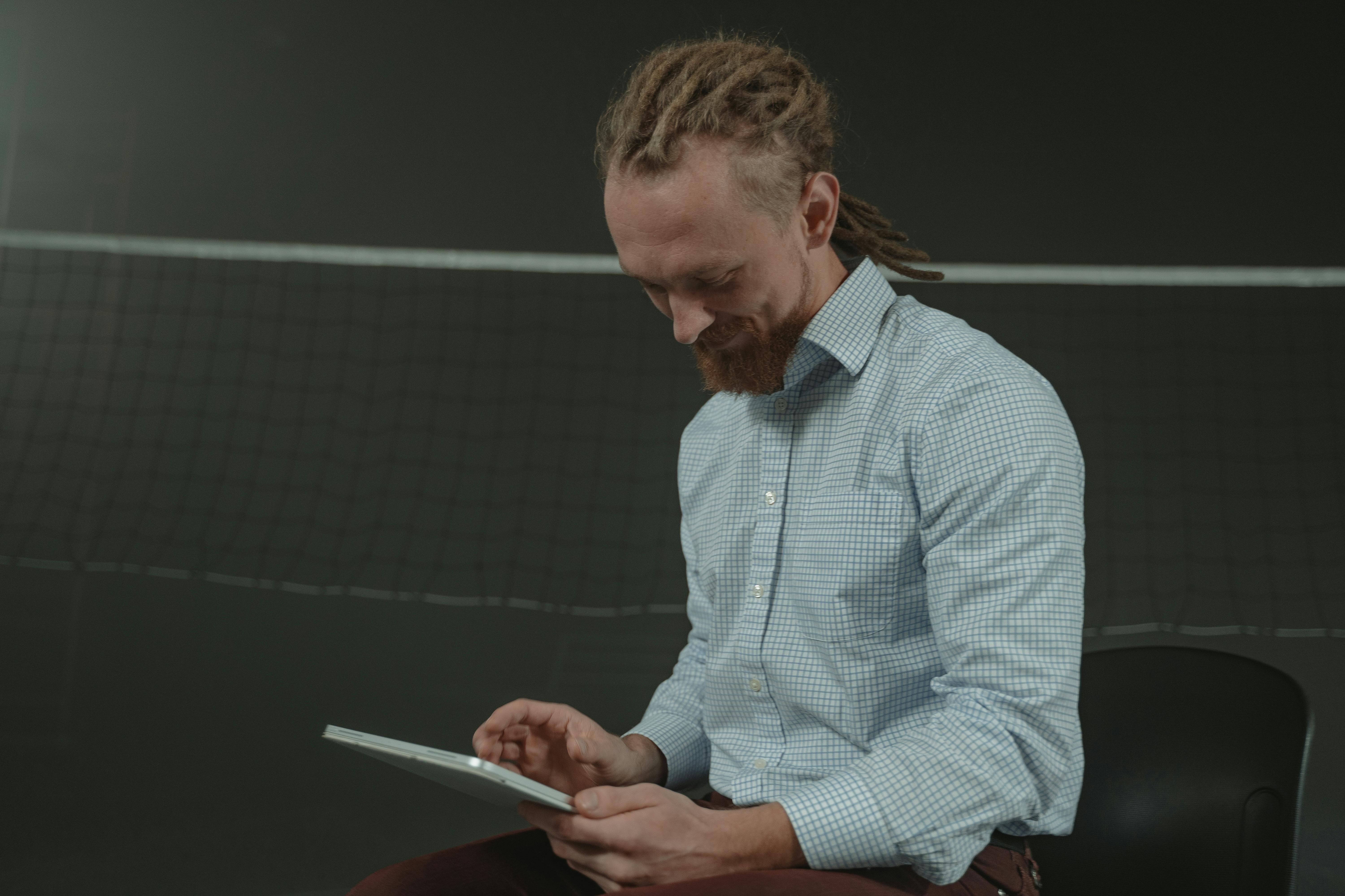 Man in White and Blue Plaid Dress Shirt Holding White Tablet Computer