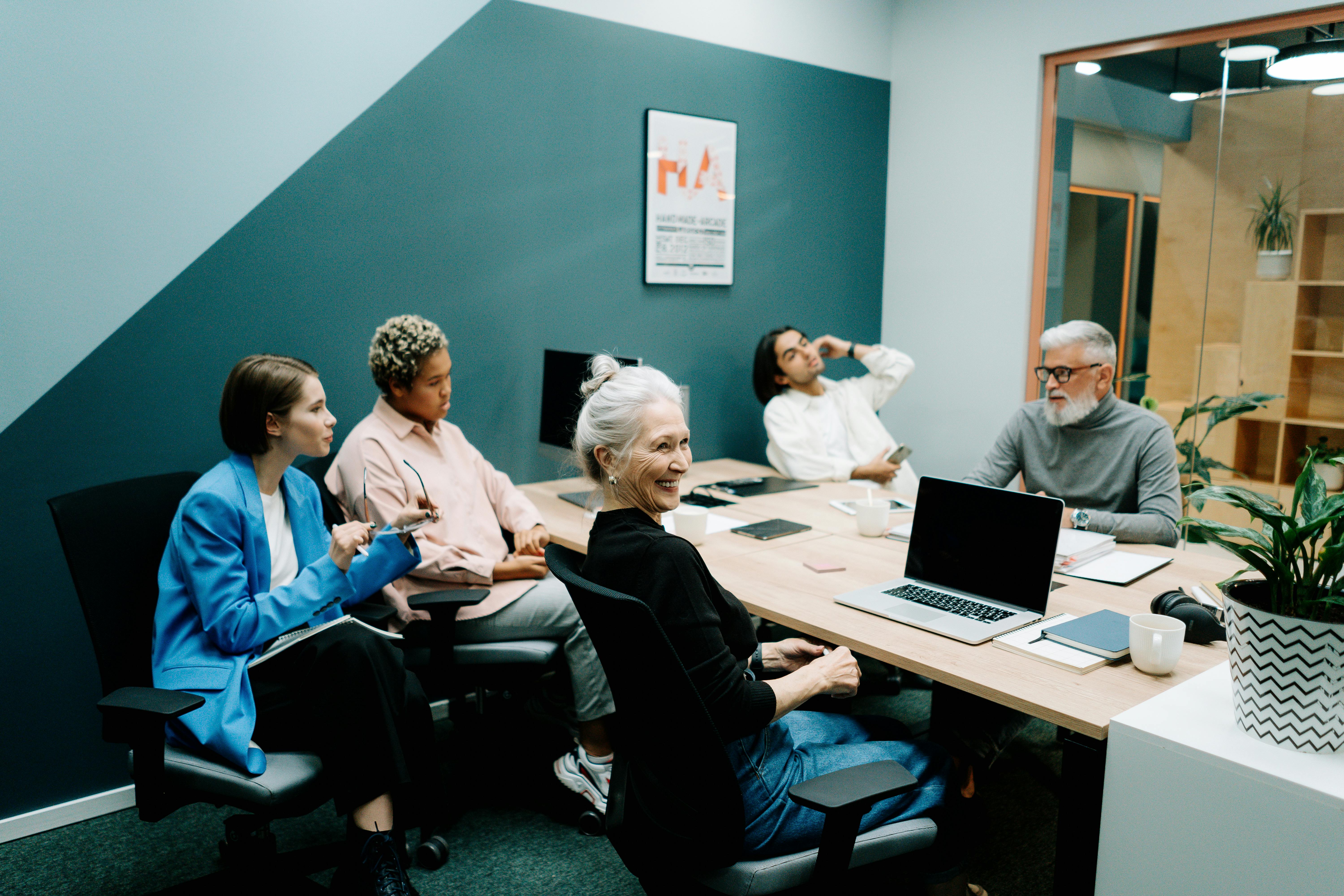 Woman in Blue Long Sleeve Shirt Sitting on Black Office Rolling Chair