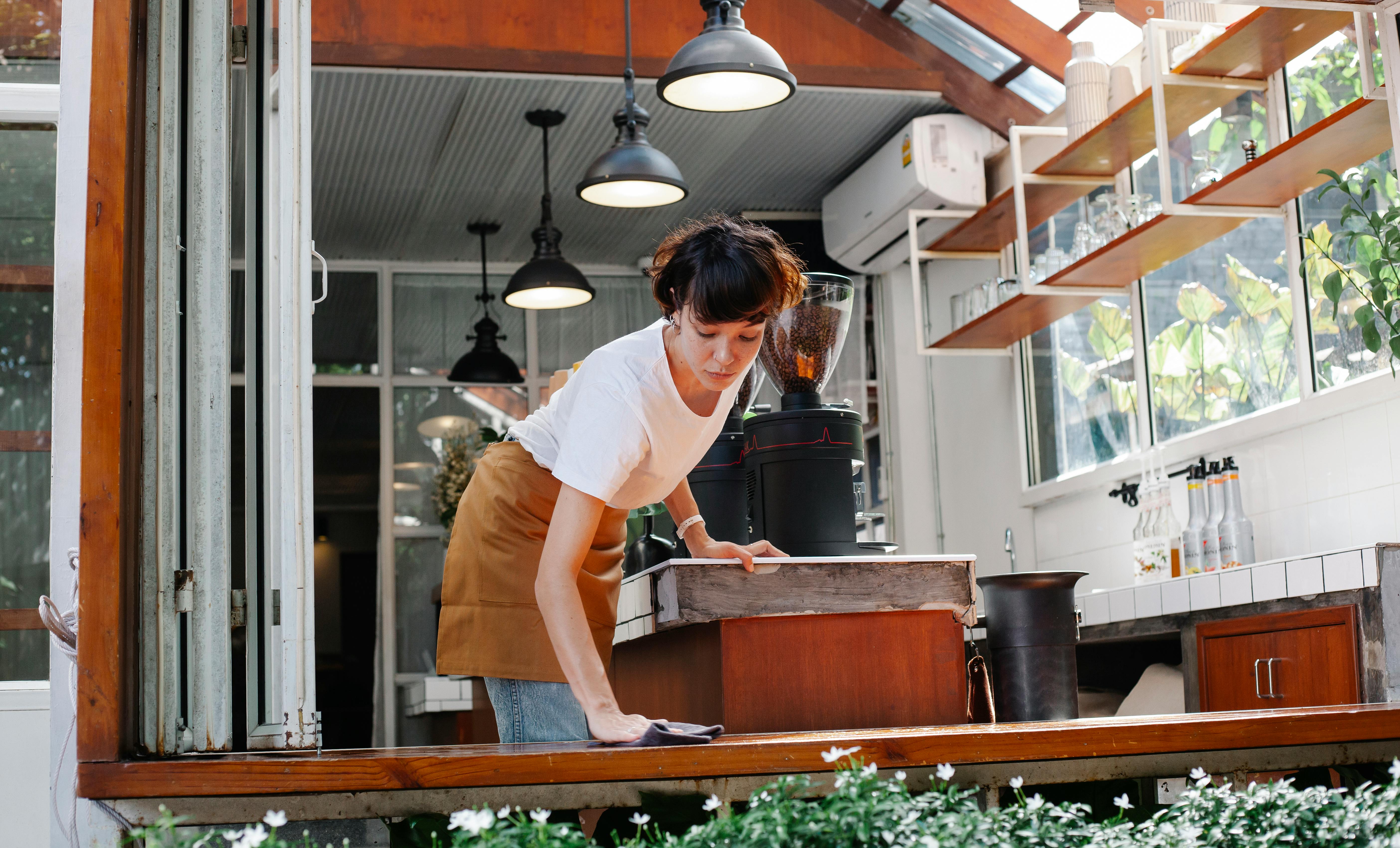 Female employee cleaning surface in cafeteria