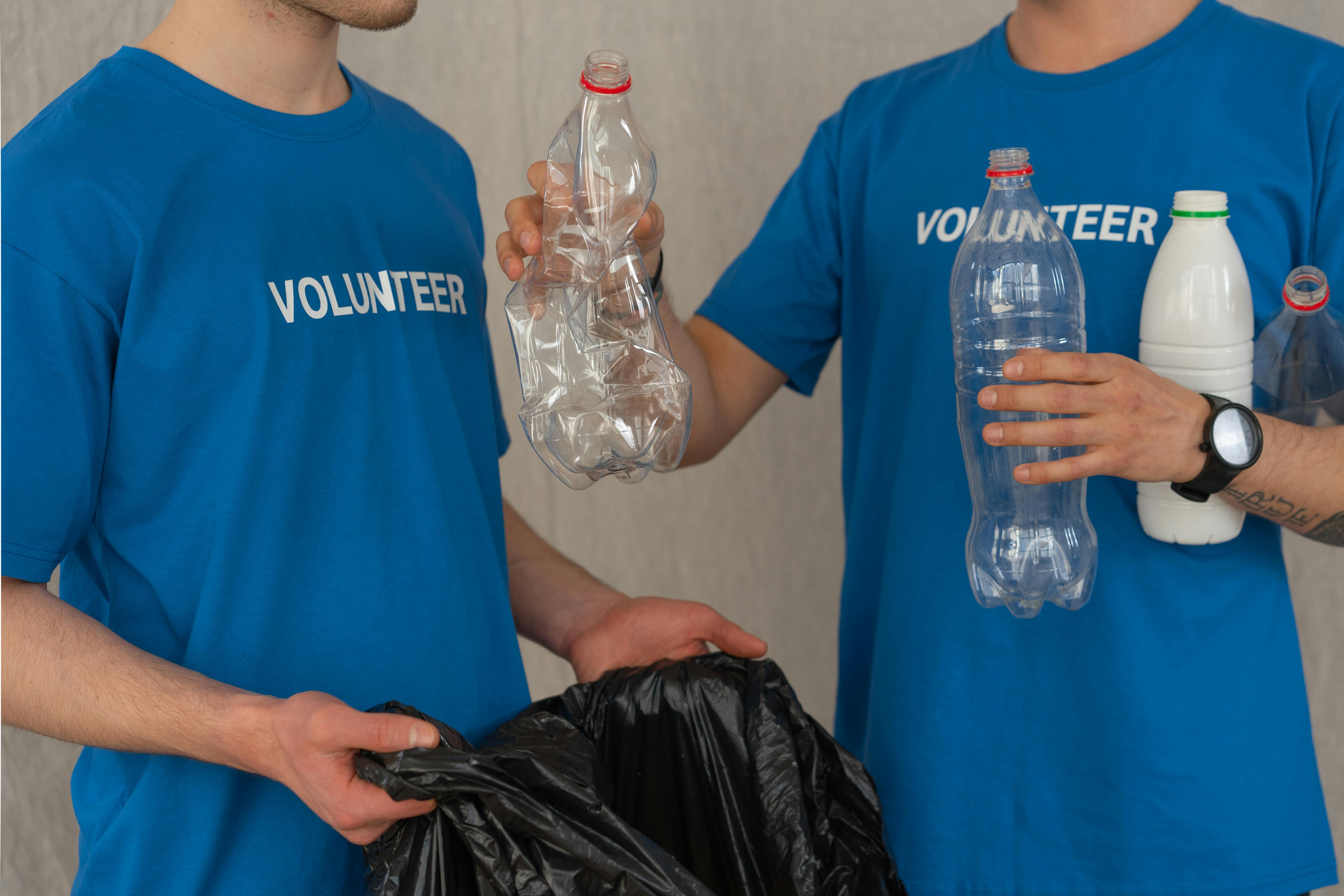 Man in Blue Crew Neck T-shirt Standing Beside Black Plastic Bag